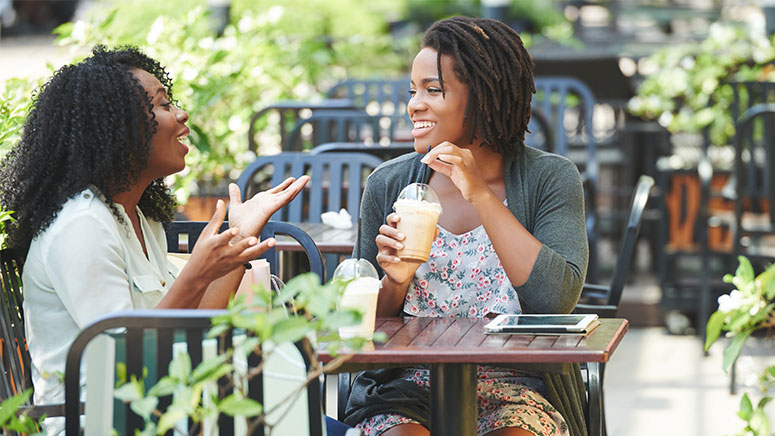 Two women chat outdoors in a city
